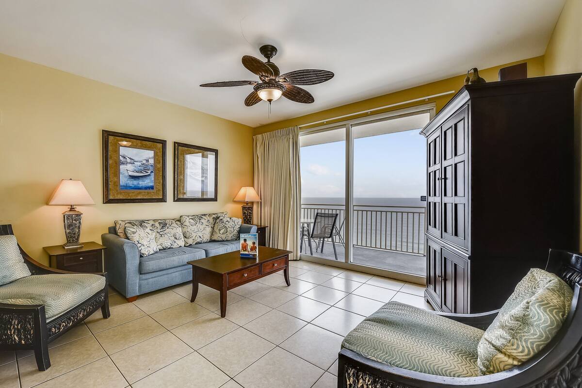 A hotel room with a balcony, a sofa, a coffee table, and a cabinet.