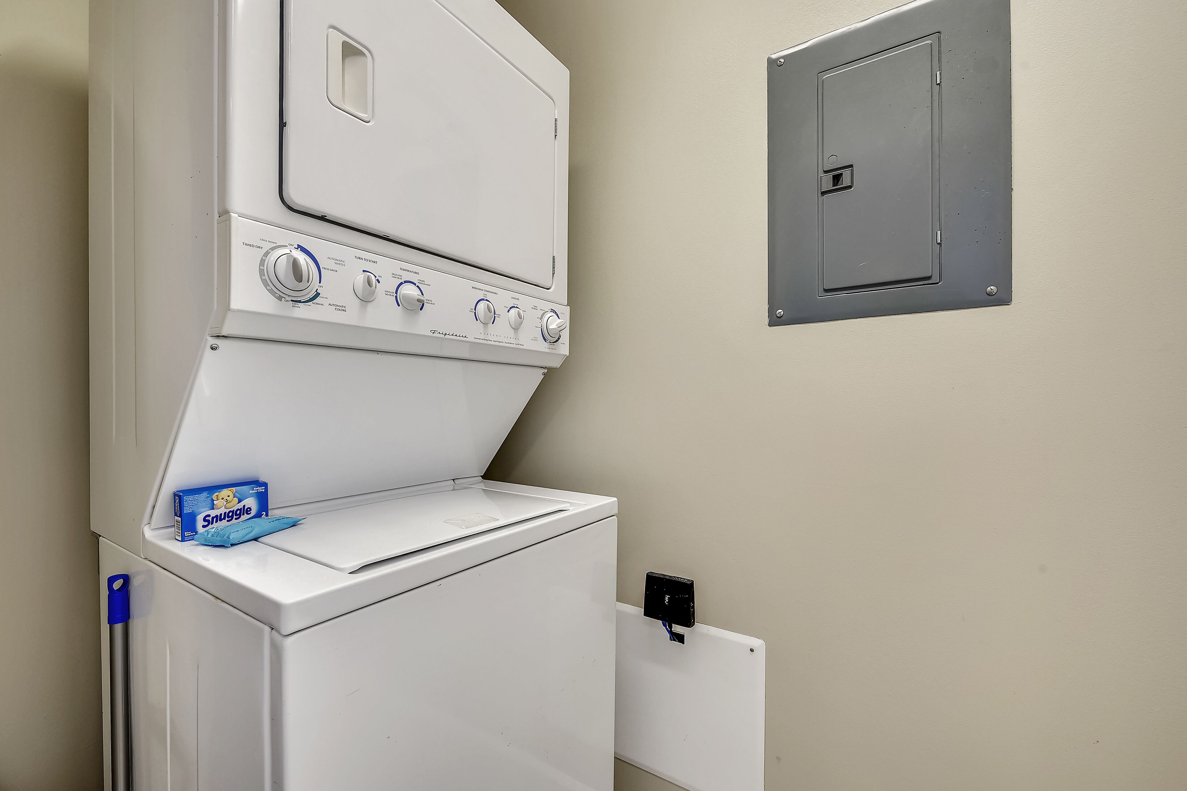 Waschmaschine und Trockner in einem Gerät mit Bedienfeld, einer Snuggle-Waschmittelbox und einer Steckdose an der Wand.