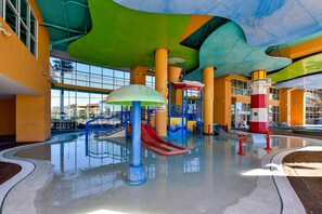 Un parc aquàtic interior amb tobogans, una zona de jocs i una piscina.