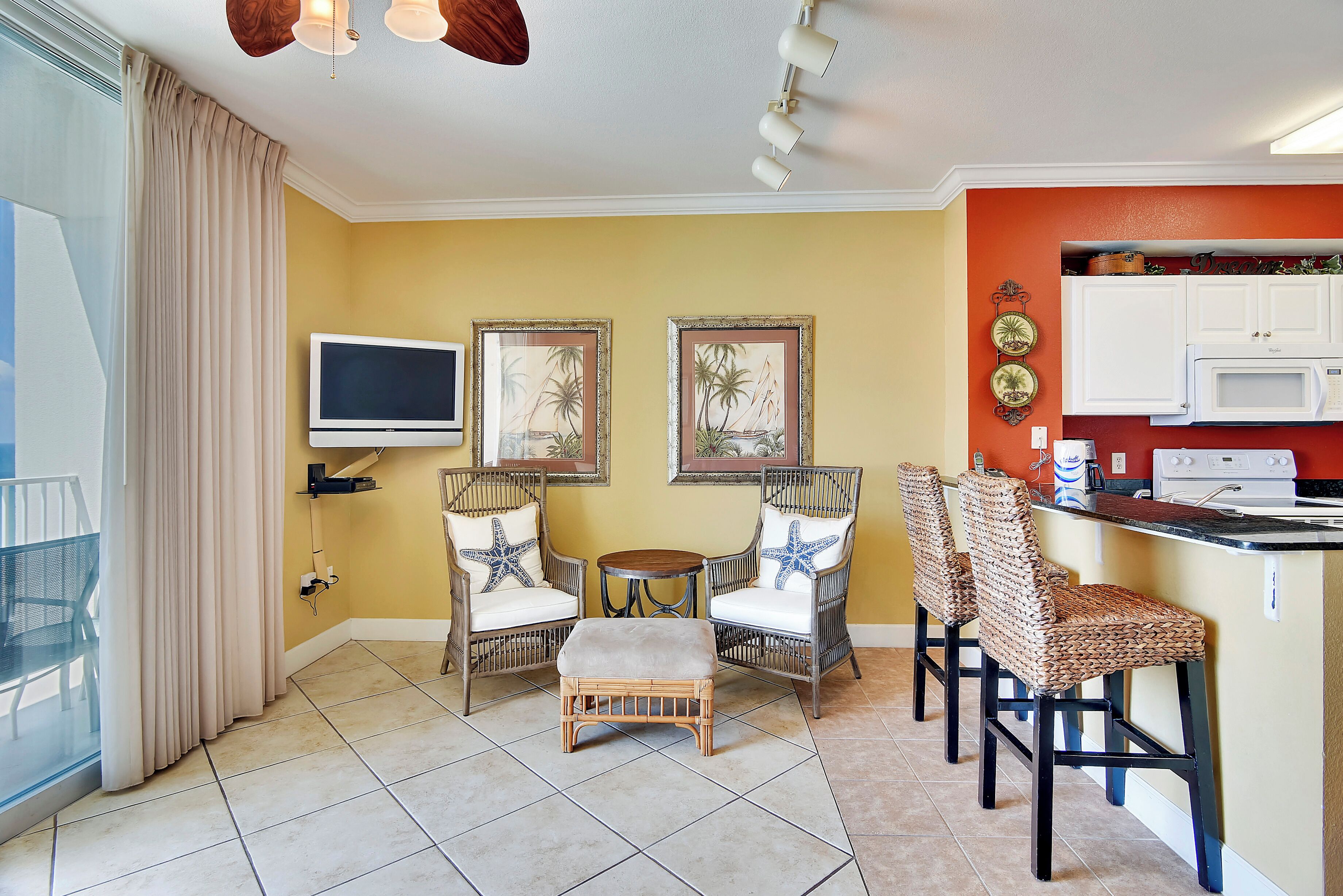 A compact living space with a dining area, kitchenette, and a TV mounted on the wall.
