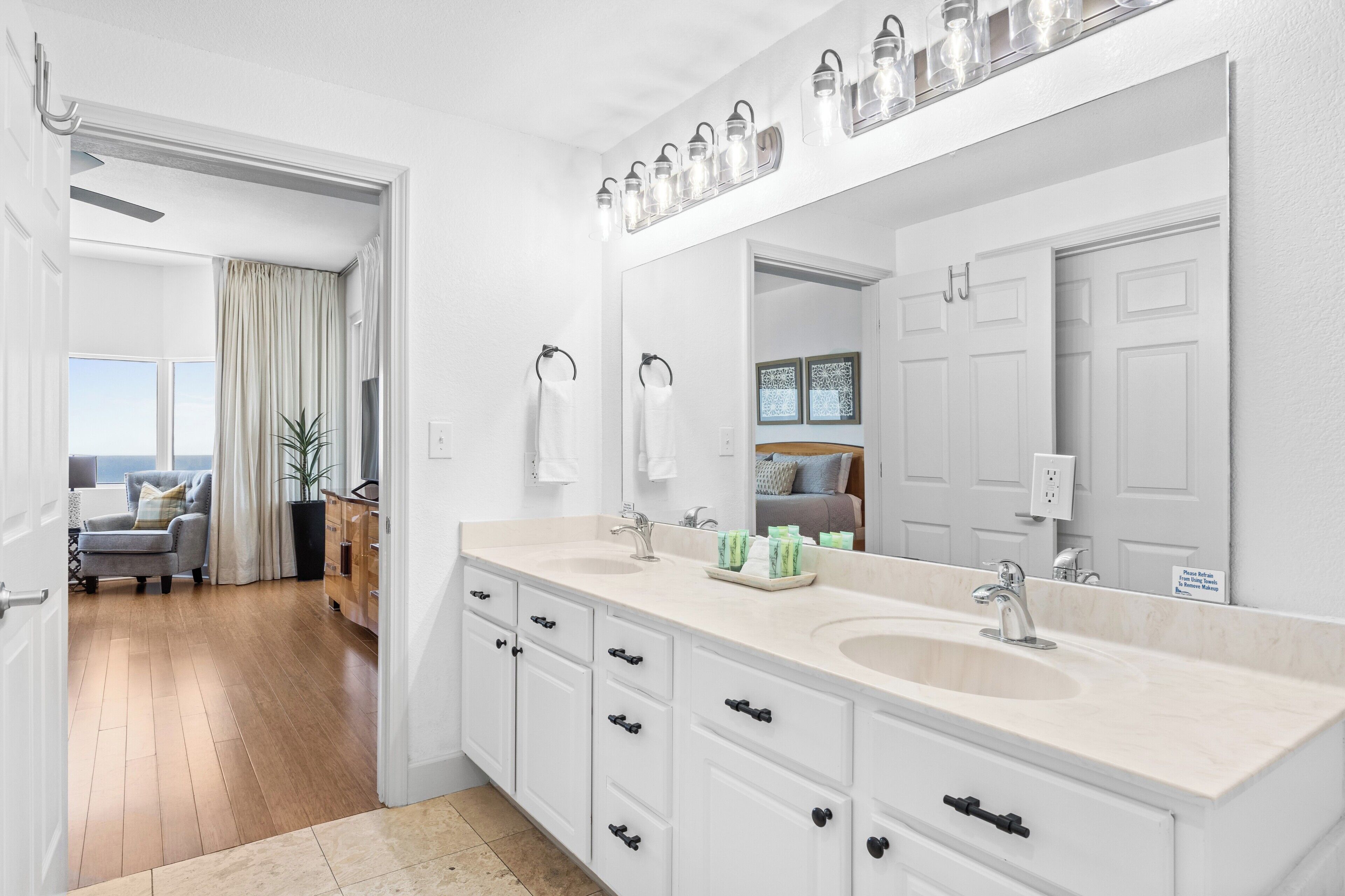 A modern bathroom with dual sinks, a large mirror, and a ceiling fan.