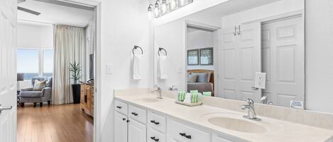 A modern bathroom with dual sinks, a large mirror, and a ceiling fan.