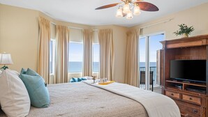 A hotel room with a large bed, a ceiling fan, a TV, and a view of the ocean. - Tidewater by Book That Condo (Panama City Beach)