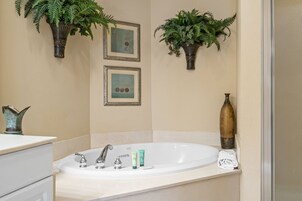 Un bagno con una vasca freestanding, due piante sospese e opere d'arte incorniciate.