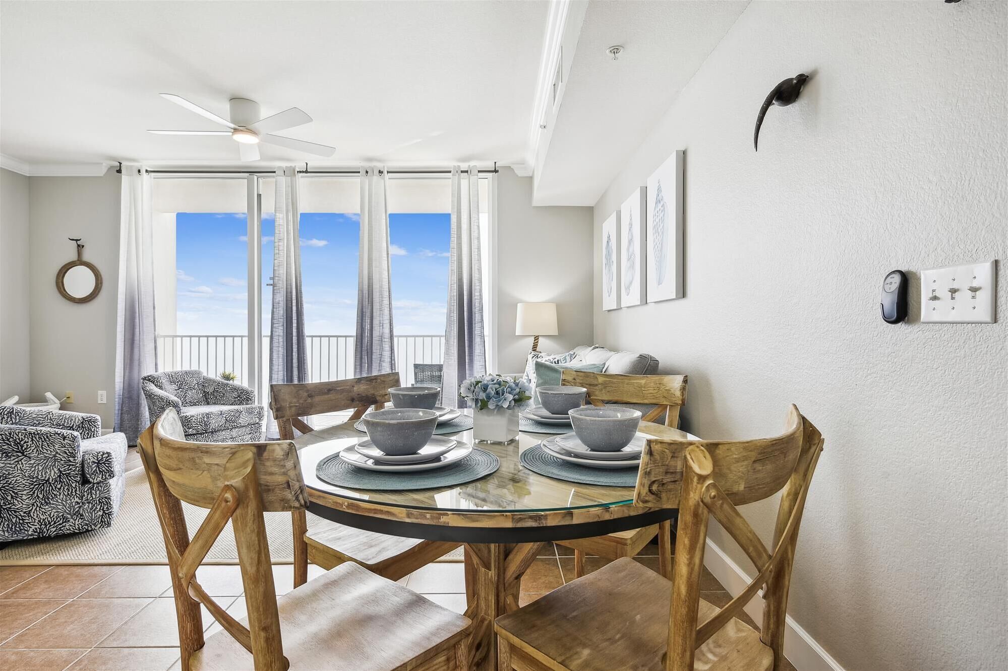 A dining area with a round table, chairs, and a view of the sky through large windows.