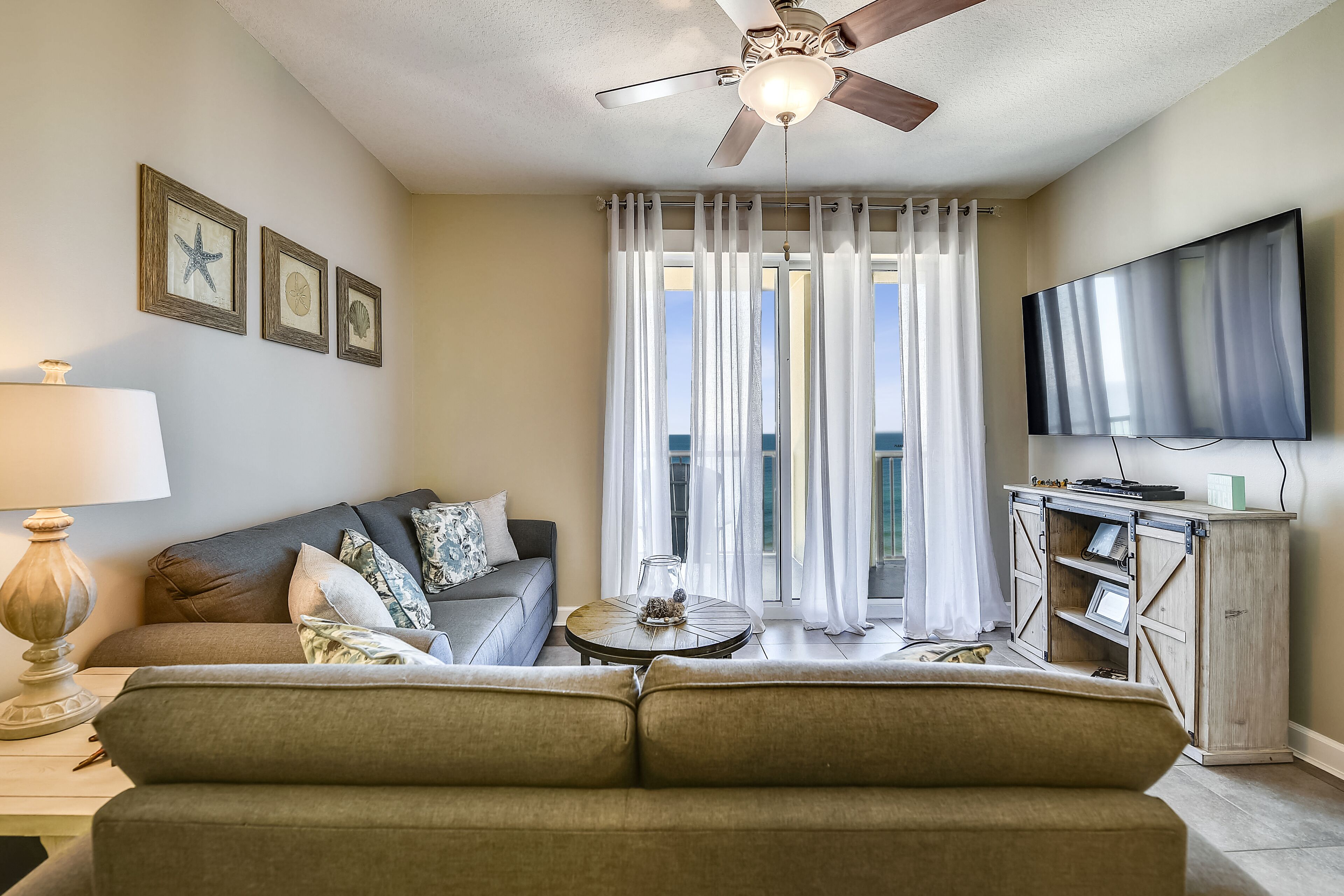 A living room with a sofa, a coffee table, a TV, and a ceiling fan.
