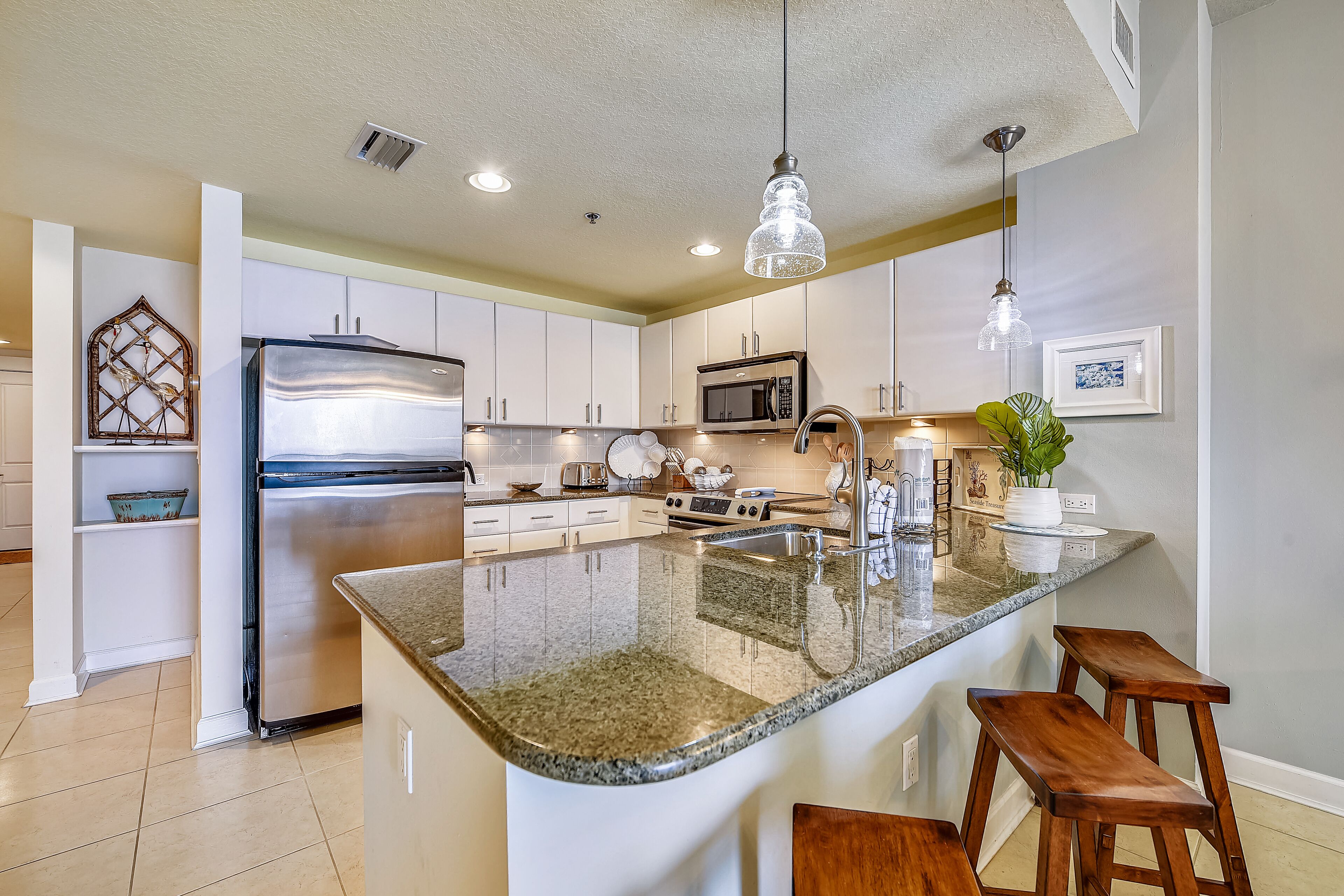 A modern kitchen with a central island, stainless steel appliances, and pendant lighting.