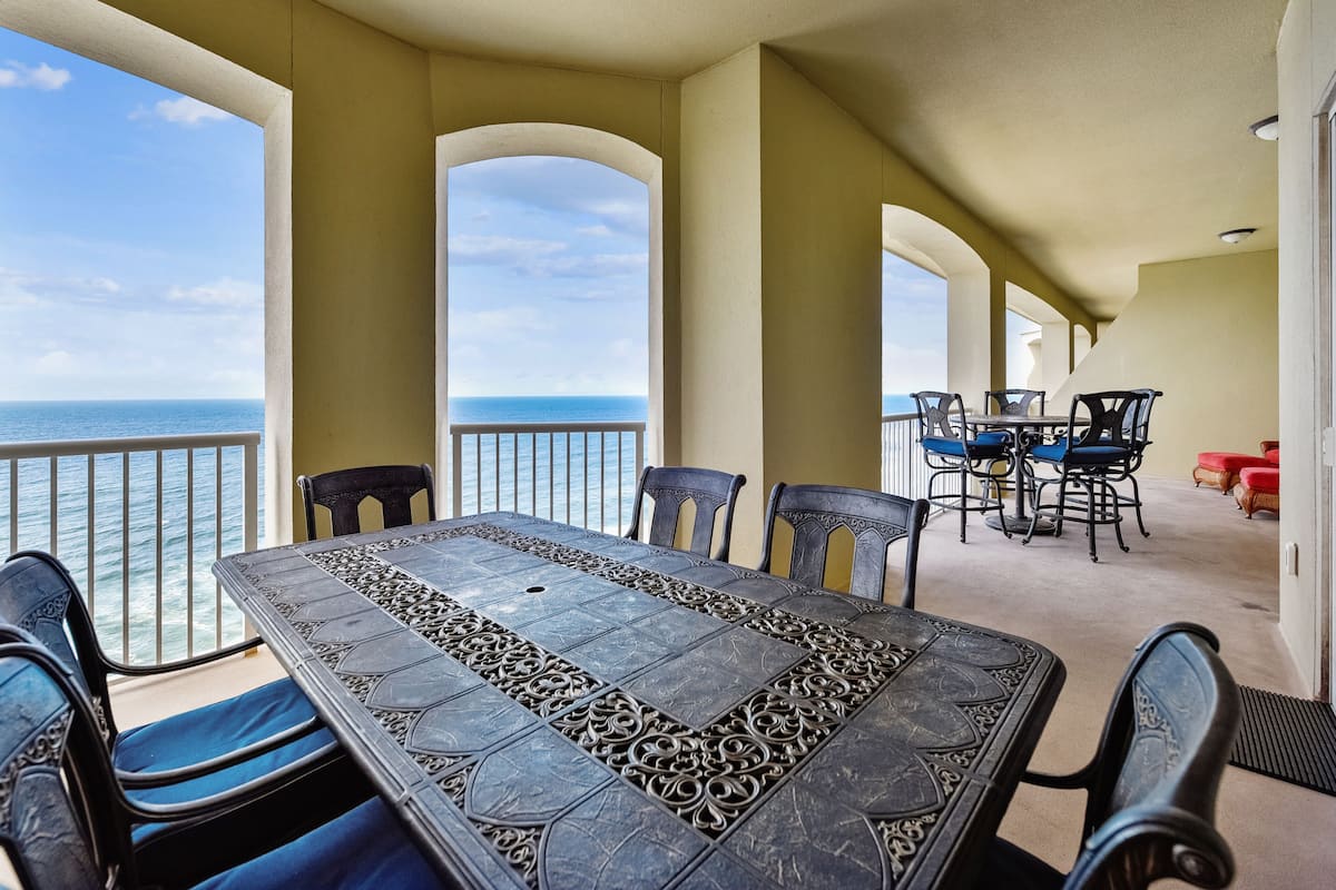 Un espace repas avec vue sur l’océan, comprenant une grande table et des chaises, ainsi qu’un coin salon séparé avec une table et des chaises.