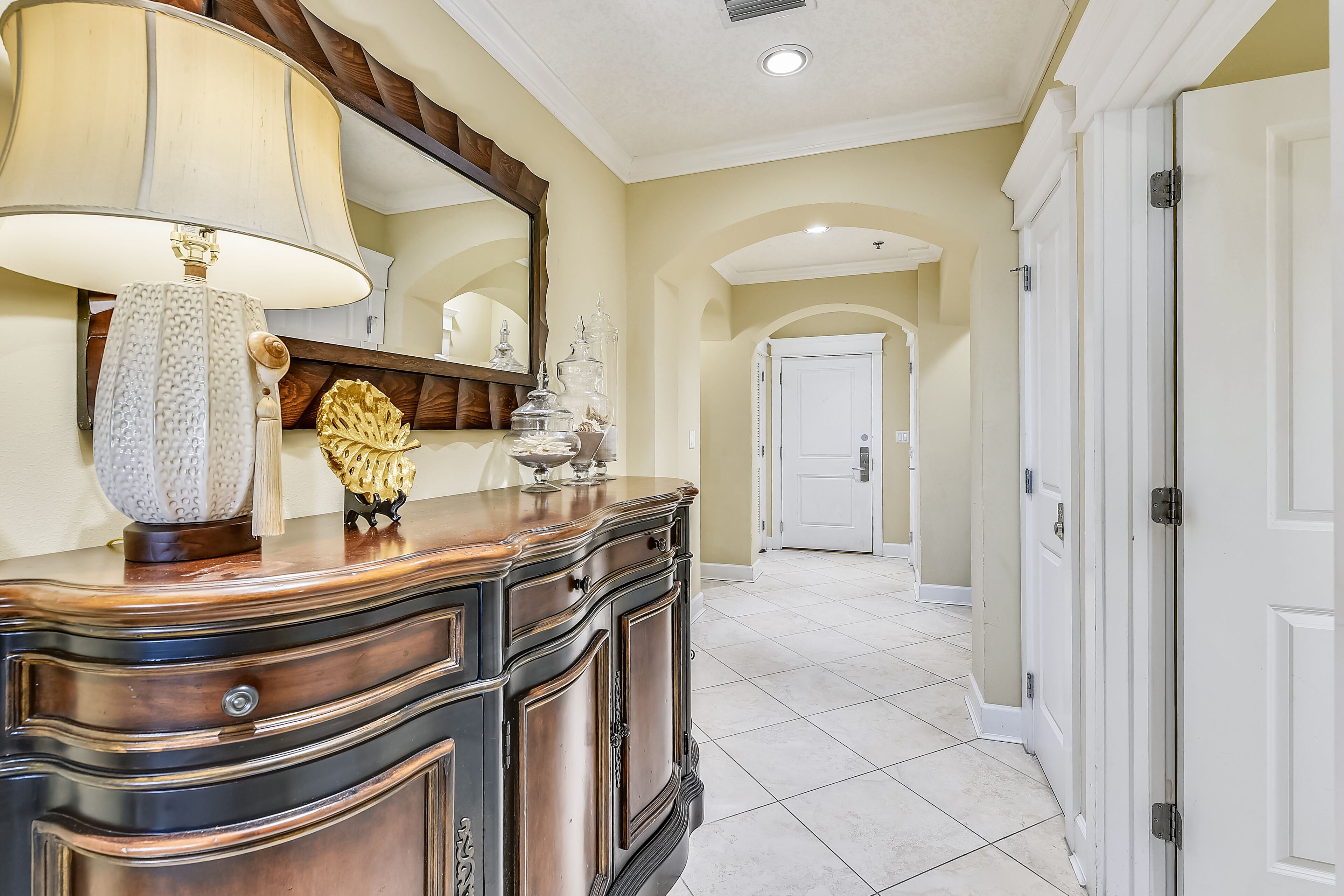 A hallway with a wooden cabinet, a lamp, and a mirror.