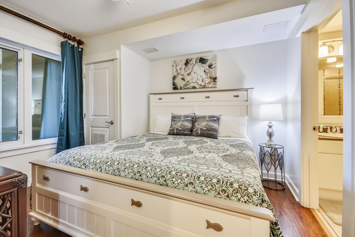 Une chambre à coucher avec un lit, une table de chevet, une lampe et un tableau au mur.