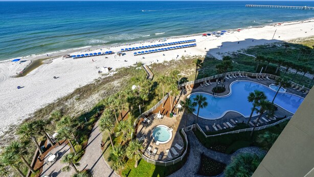 A beach resort with a swimming pool, beach umbrellas, and a pier in the background. - Grand Panama Beach Resort by Book That Condo (Panama City Beach)