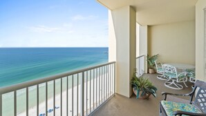 A balcony with a view of the ocean, white outdoor furniture, and potted plants. - Grand Panama Beach Resort by Book That Condo (Panama City Beach)