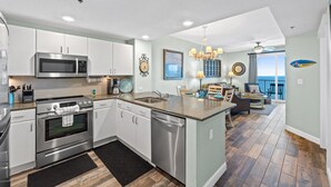 A modern kitchen with stainless steel appliances, a dining area with a view, and a spacious living room. - Grand Panama Beach Resort by Book That Condo (Panama City Beach)