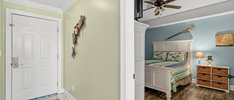 Un dormitorio con cama, mesita de noche, ventilador de techo y lámpara de pared.
