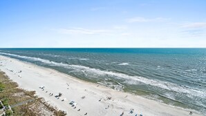 Una playa con una extensa orilla de arena, algunas sombrillas y algunas personas.