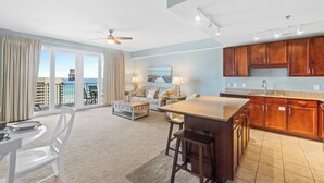 A spacious living area with a kitchen, large windows, and a balcony with a view.