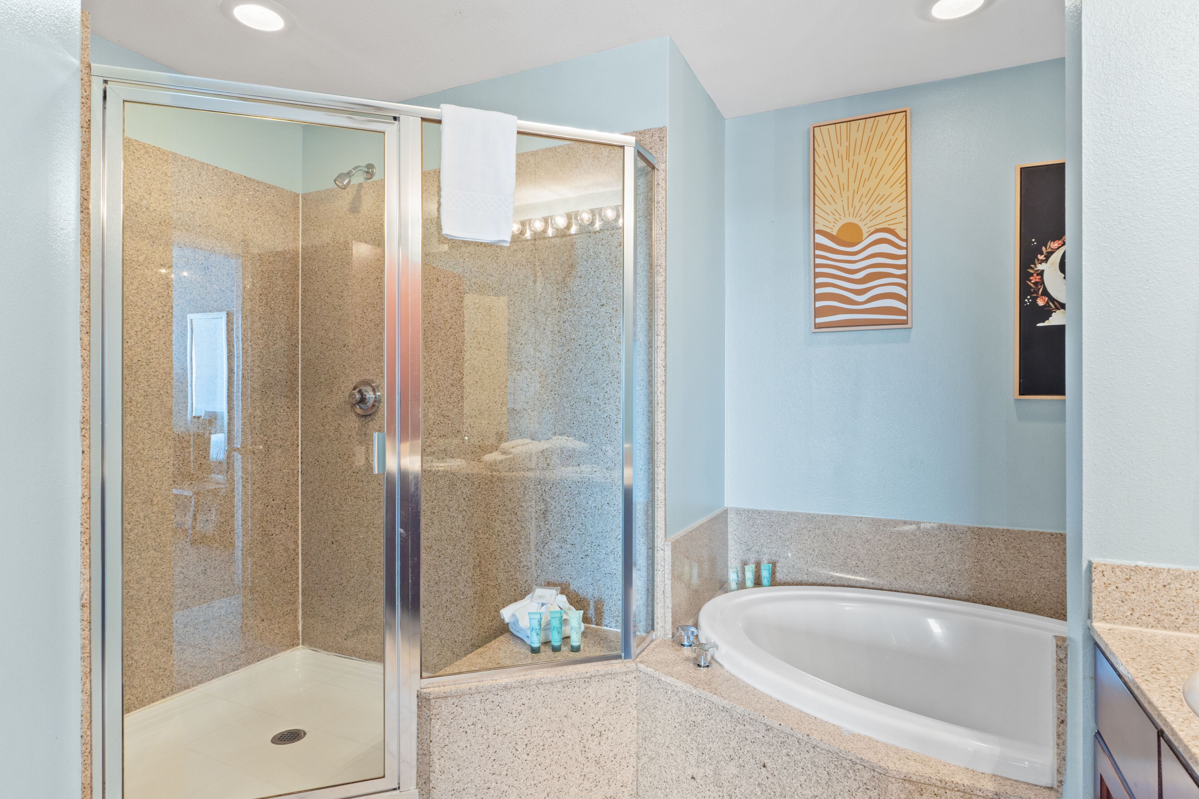 Une salle de bain moderne dotée d’une douche à parois de verre, d’une baignoire sur pieds et d’un lavabo fixé au mur.
