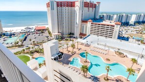 A hotel with multiple swimming pools, a beach view, and a parking area.