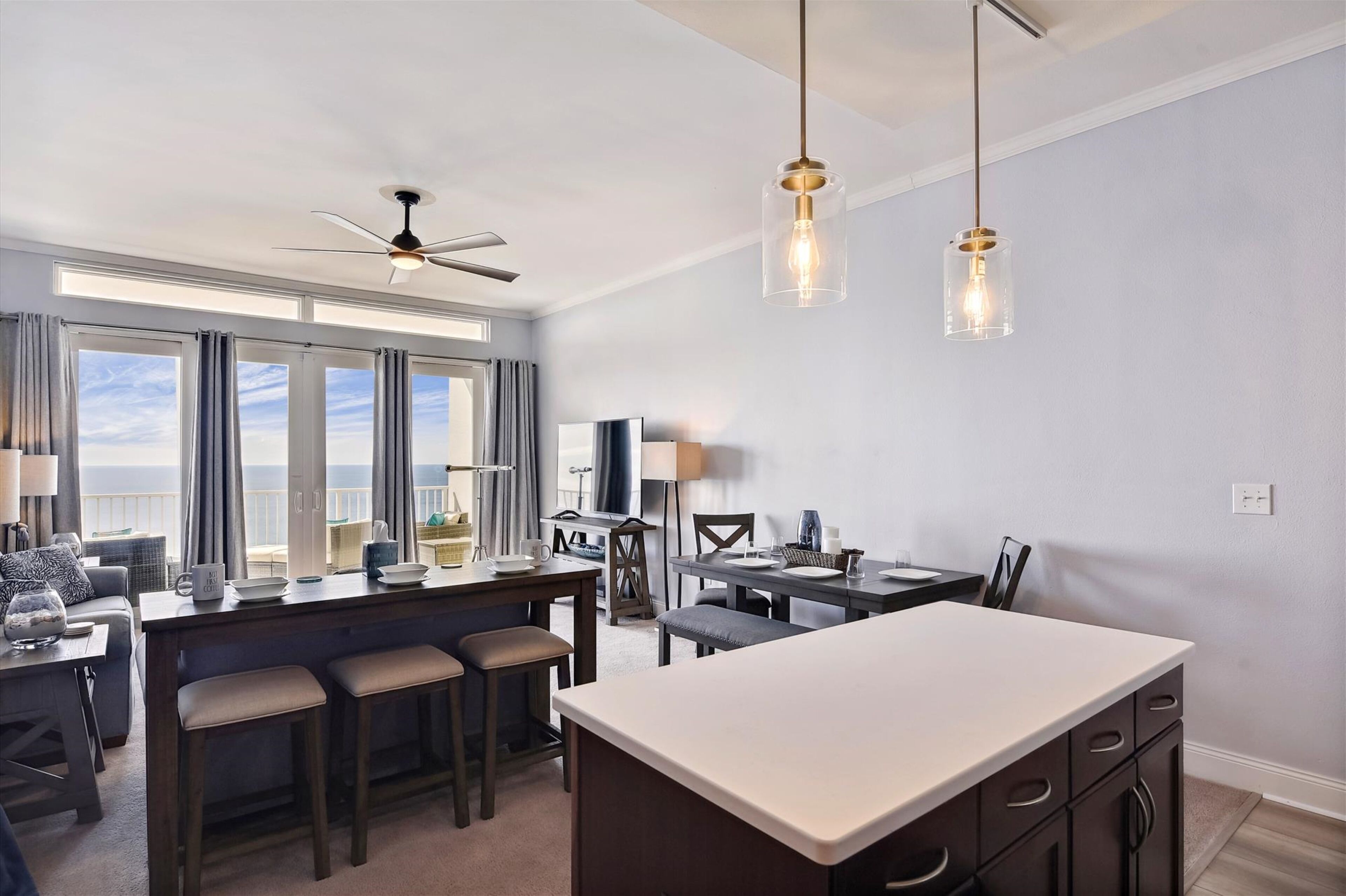 A modern kitchen with a central island, bar stools, and pendant lighting.