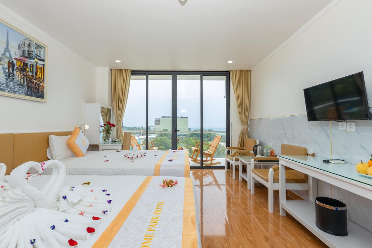 A hotel room with a bed, a desk, a TV, and a view of the city.