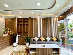 A modern living room with a sofa, a coffee table, a potted plant, and a decorative flower arrangement.