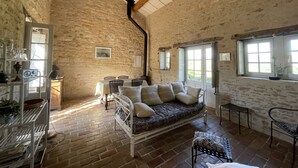 Une pièce rustique avec un mur en pierre, un plafond en bois, un canapé, une table et une fenêtre.