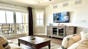 A living room with a sofa, coffee table, and a TV mounted on the wall.