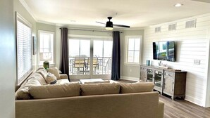A living room with a sofa, a ceiling fan, and a TV.