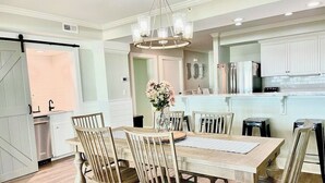 A spacious kitchen with white cabinets, a central island, and a dining area with wooden chairs and a table.