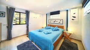 A bedroom with a bed, curtains, a window, and a wall-mounted artwork. - Finca Stemann - Casa Pascal (Guia de Isora)