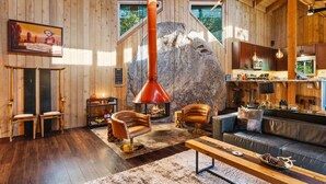 A cozy wooden interior with a fireplace, leather furniture, and a large rock feature. - Unique Modern Cabin w/spa, dry sauna (Idyllwild)