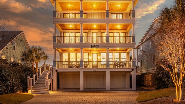 A multi-story building with a central entrance, upper balconies, and a garage. - 6-Bedroom Luxury House with Pool, Steps to Beach (Isle of Palms)