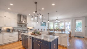 A modern kitchen with white cabinets, a central island, and pendant lighting. - 6-Bedroom Luxury House with Pool, Steps to Beach (Isle of Palms)