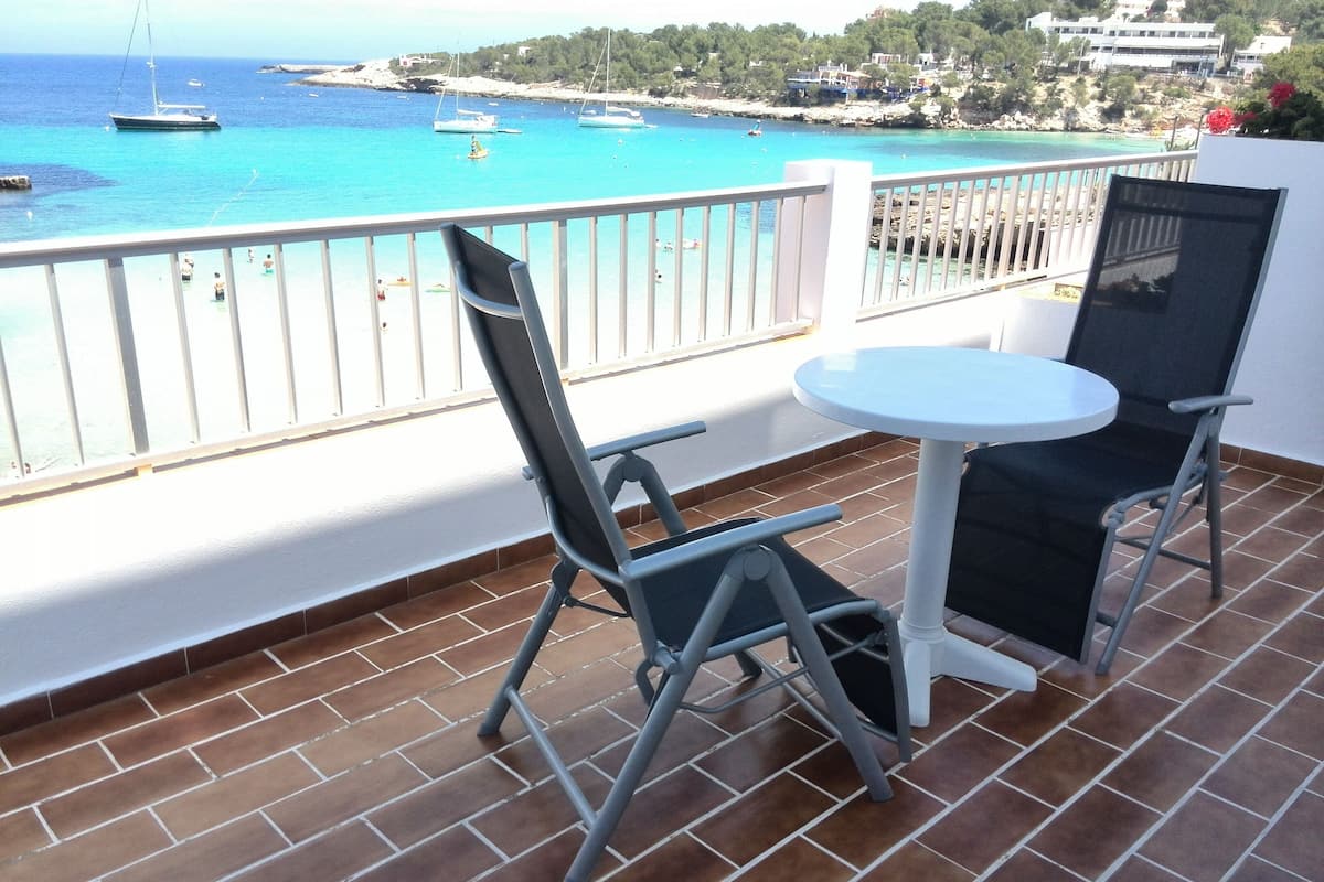 Un balcon doté d’un sol carrelé, de deux chaises et d’une petite table ronde.