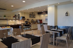 Een restaurant met een buffetgedeelte, eettafels en stoelen.