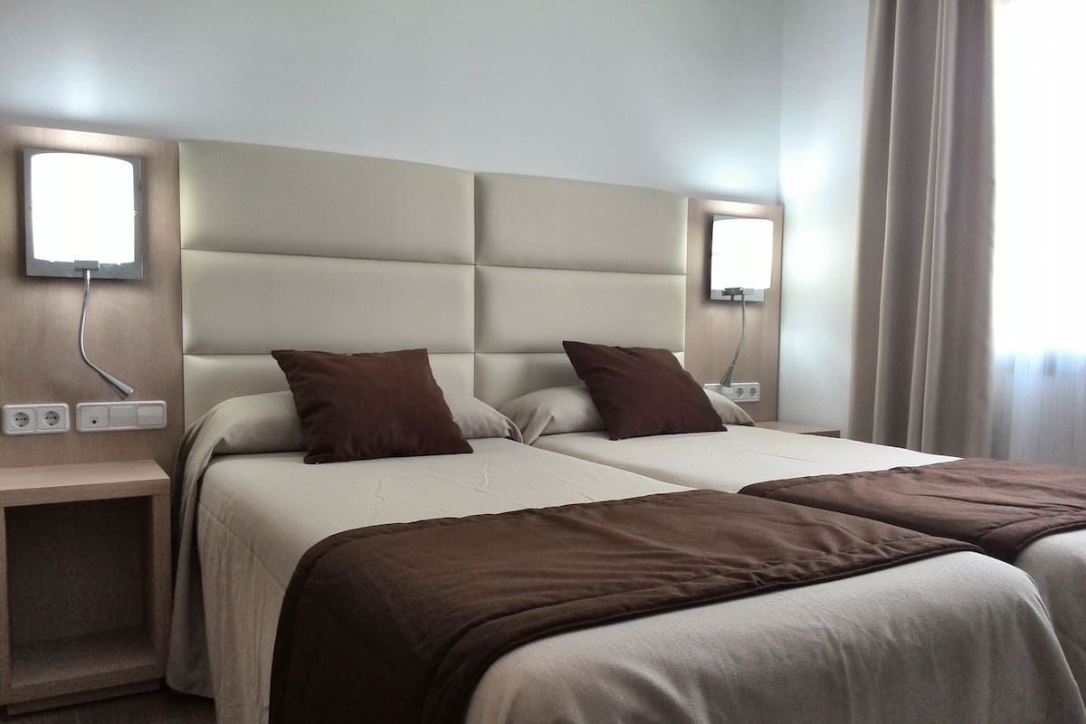 Une chambre d’hôtel avec deux lits, chacun doté d’une tête de lit, de tables de chevet et de lampes.