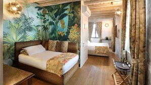 Quarto com cama, escrivaninha e espelho. Apresenta um mural tropical na parede e piso de madeira.