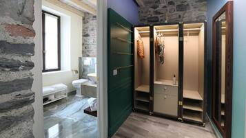 Un baño con pared de piedra, ventana, inodoro, lavabo y puerta verde.
