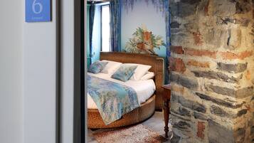 Un dormitorio con cama, pared de piedra y suelo de madera.