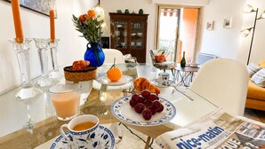 A dining table with a newspaper, a croissant, grapes, a glass of orange juice, and a cup of coffee. - l'Appartement Magnolia (Vallauris)