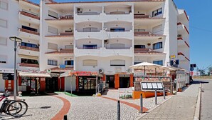 Un edificio a più piani con balconi, una colonnina di servizio a livello strada e una bicicletta parcheggiata davanti.