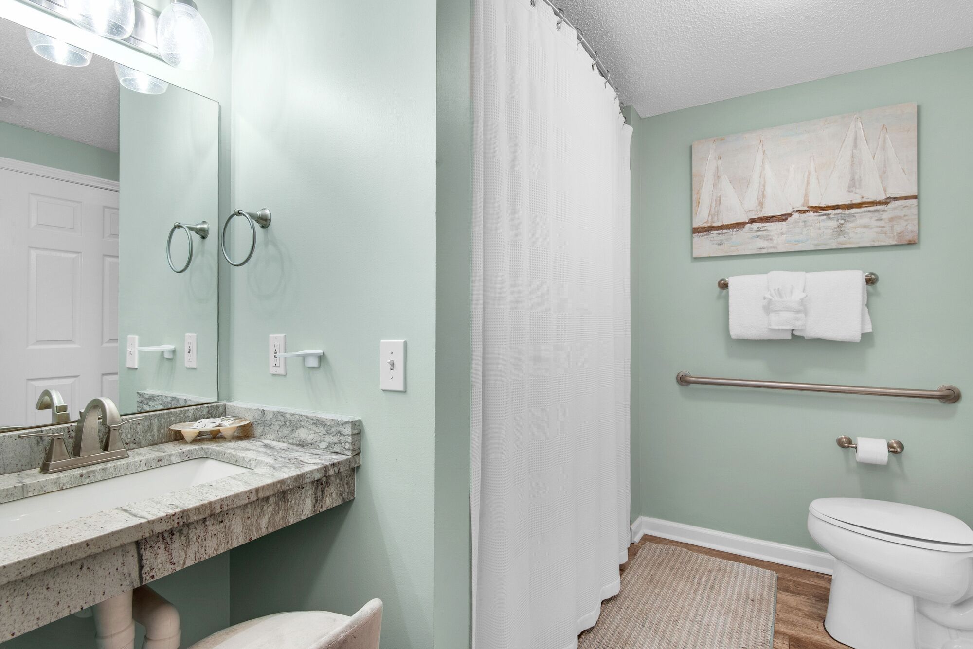 Ein Badezimmer mit Marmorwaschbecken, Handtuchhalter, Toilette und Duschvorhang.