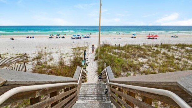 A beach view with a wooden staircase leading to the sand, a flagpole, and beach umbrellas. - 30A 5 Minute Walk to Beach / Private Heated Pool / View / Family Vacation (Santa Rosa Beach)