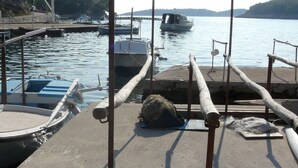 Un quai avec un petit bateau, une plateforme en béton et une côte rocheuse en arrière-plan.