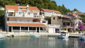 Un bâtiment situé sur la côte, doté de nombreux balcons, d’une façade en pierre et d’un toit recouvert de tuiles.