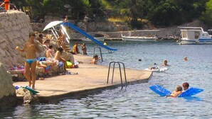 Une plage où l’on peut se baigner et bronzer, avec des bateaux sur l’eau et une côte rocheuse.