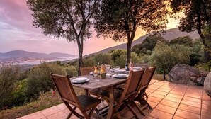 Una mesa de comedor al aire libre dispuesta en un patio con vistas panorámicas a un valle y montañas.