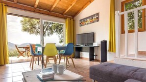 Una habitación con zona de comedor, televisión y sofá.