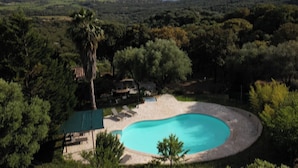 Una piscina rodeada de jardines con vistas a montañas distantes y una masa de agua.