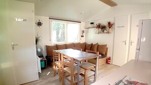 Een gezellig, compact verblijf met een eettafel, houten stoelen, een bank en een kleine kitchenette.